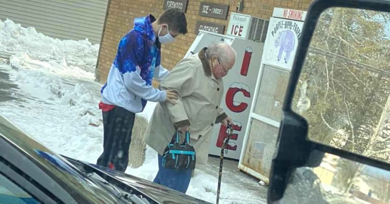 man-helps-elderly-woman-walk-across-ice